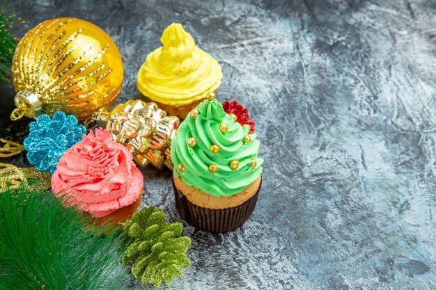 Vooraanzicht kleurrijke cupcakes kerst ornamenten op grijze achtergrond vrije plaats