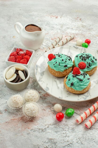 Vooraanzicht kleurrijke snoepjes met slagroomtaarten op witte achtergrond biscuit zoete cake cookie sugar