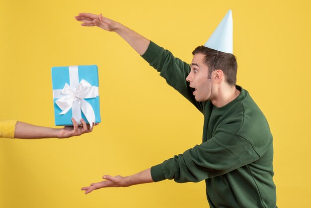 Vooraanzicht knappe jongeman geschenk nemen van menselijke hand op geel