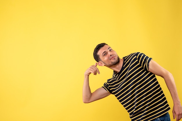 Vooraanzicht knappe man in zwart-wit gestreept t-shirt bel me telefoongebaar maken op gele geïsoleerde achtergrond