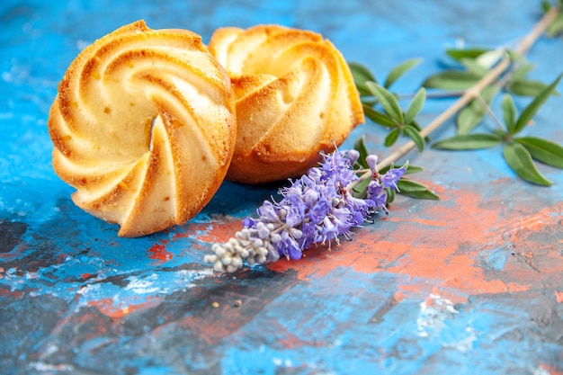 Gratis foto vooraanzicht koekjes paarse bloemen op blauwe tafel