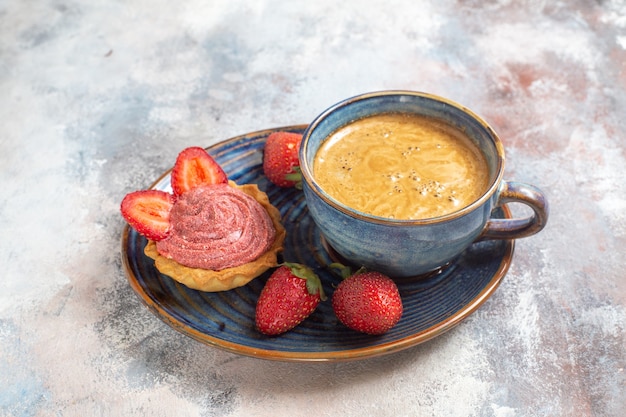 Gratis foto vooraanzicht kopje koffie met cake en aardbeien op lichte achtergrond