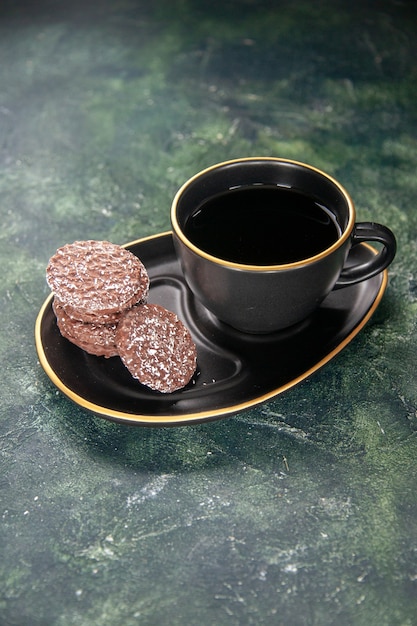 Gratis foto vooraanzicht kopje thee in zwarte kop en plaat met koekjes op donkere ondergrond kleur suikerglas ontbijt dessert cake cookie