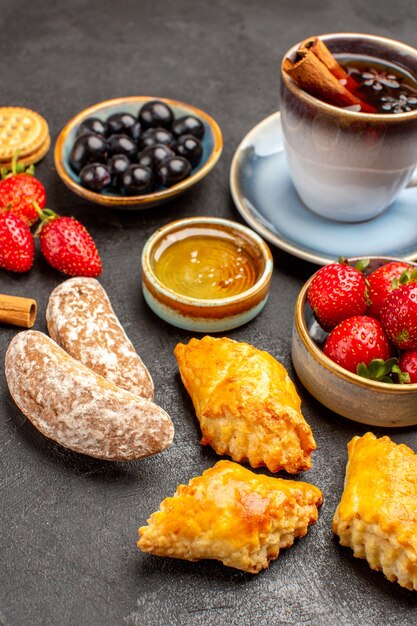 Vooraanzicht kopje thee met koekjes en fruit op de donkere zoete cake van het oppervlaktefruit