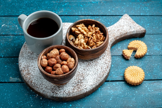Vooraanzicht kopje thee met walnoten en hazelnoten op de blauwe rustieke kleur van de de snackthee van de bureaunoot
