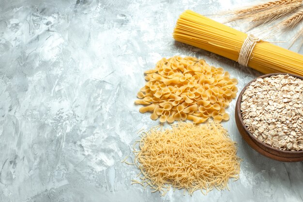 Vooraanzicht lange italiaanse pasta met verschillende gevormde rauwe kleine pasta op lichte foto voedselkleur veel deeg