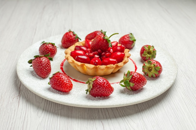 Vooraanzicht lekkere cake met vers fruit binnen plaat op wit de cakedessert van het bureaufruit