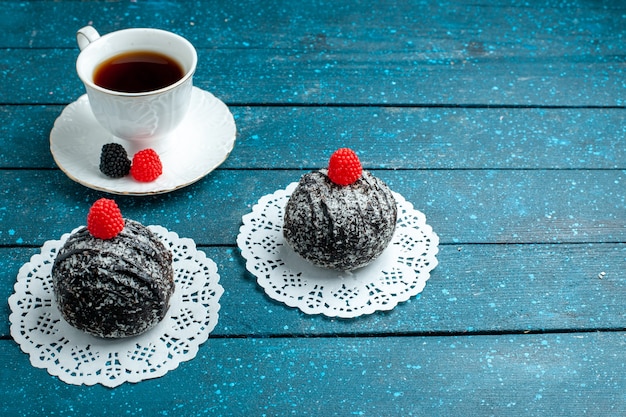 Vooraanzicht lekkere chocoladeballen met kopje thee op het blauwe rustieke van het de cakekoekje van de bureauthee het koekjeskoekje