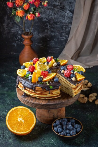 Vooraanzicht lekkere chocoladetaart met fruit op donkere muur