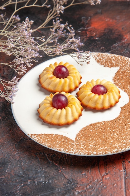 Gratis foto vooraanzicht lekkere kleine koekjes binnen plaat op donkere tafel cake zoete koekjes