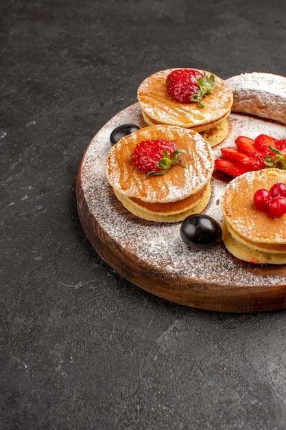 Vooraanzicht lekkere pannenkoeken met fruit en cakes op de donkere zoete cake van het oppervlaktefruit Gratis Foto