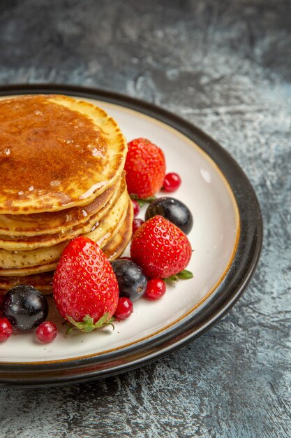 Vooraanzicht lekkere pannenkoeken met fruit en honing op licht oppervlak ontbijt zoet fruit