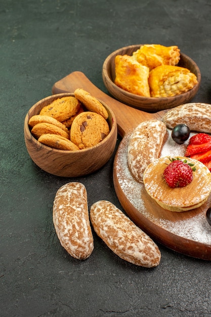 Vooraanzicht lekkere pannenkoeken met fruit en zoete cakes op het donkere dessert van de oppervlakte zoete cake