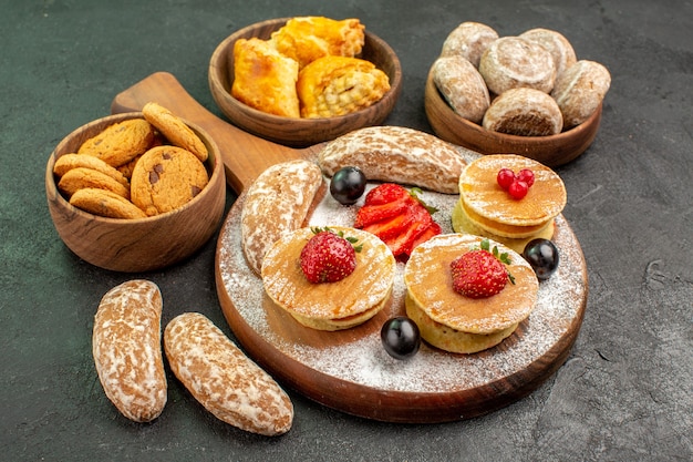 Vooraanzicht lekkere pannenkoeken met fruit en zoete cakes op het donkere dessert van de oppervlakte zoete cake