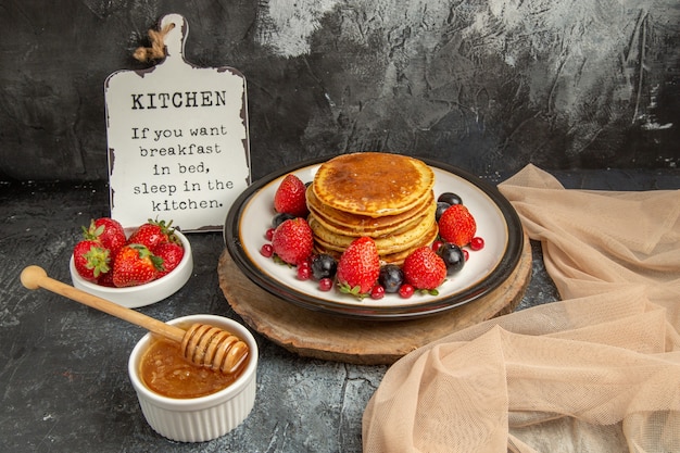 Vooraanzicht lekkere pannenkoeken met honing en fruit op het lichte oppervlak zoete melkfruit