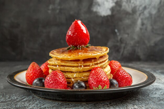 Vooraanzicht lekkere pannenkoeken met vers fruit op lichte vloer ontbijt zoet fruit