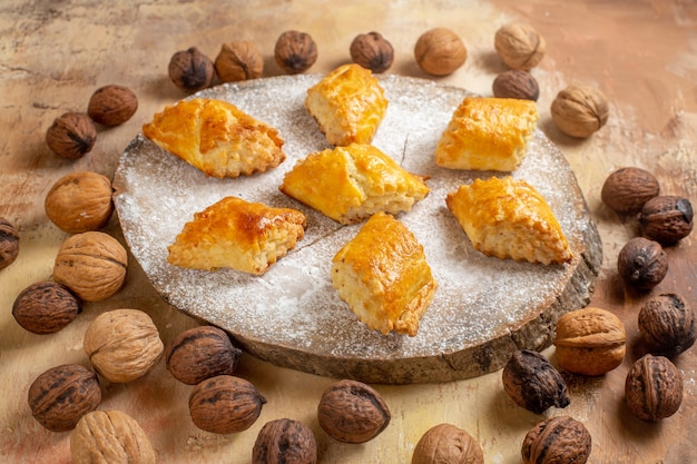 Vooraanzicht lekkere walnootgebakjes met walnoten op lichte tafel zoete taartgebakcake