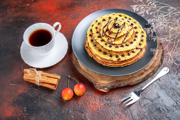 Vooraanzicht lekkere zoete pannenkoeken met thee op donkere achtergrond