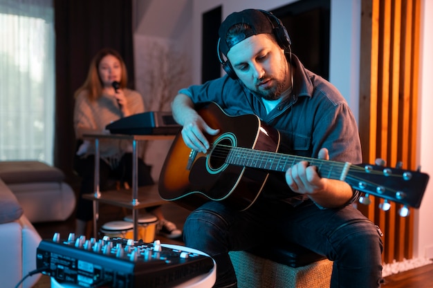 Vooraanzicht man die gitaar binnenshuis speelt