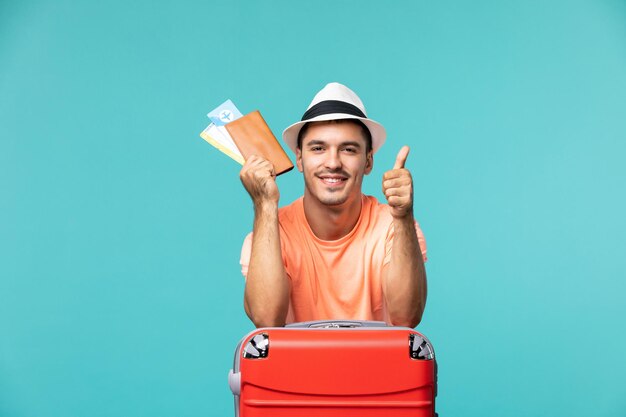 Vooraanzicht man in vakantie met zijn kaartjes op blauw