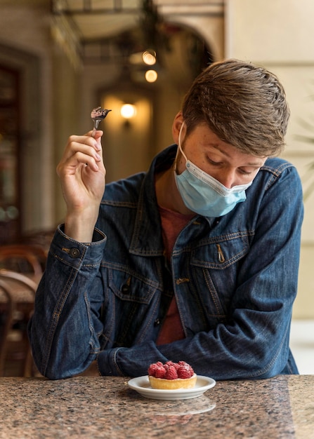 Vooraanzicht man met gezichtsmasker genieten van een cake
