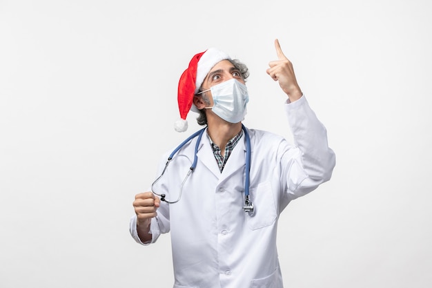 Vooraanzicht mannelijke arts in steriel masker op witte nieuwjaarsvakantie van het bureauvirus