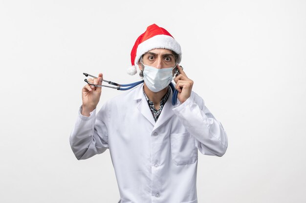 Vooraanzicht mannelijke arts met masker op een witte muur vakantie covid pandemisch virus