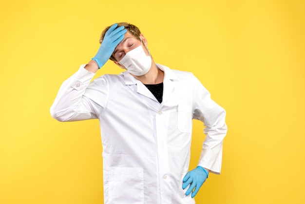 Vooraanzicht mannelijke arts moe op gele achtergrond pandemische covid gezondheidsmedicijn