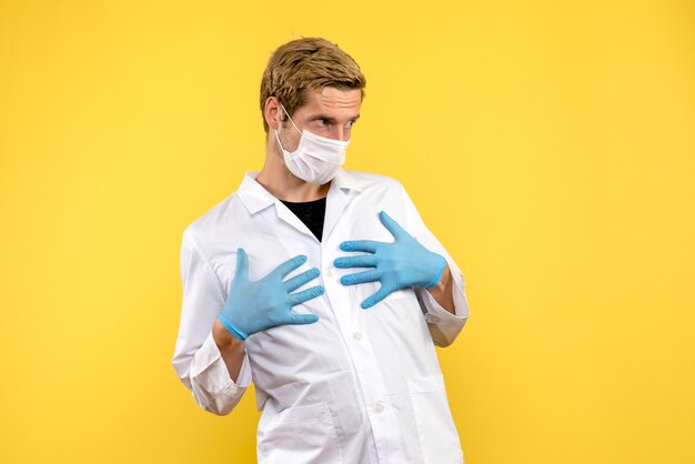 Vooraanzicht mannelijke arts op gele achtergrond pandemische medic gezondheid covid-