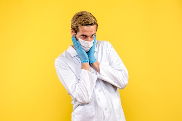 Vooraanzicht mannelijke arts poseren op gele achtergrond pandemic medic health covid-virus