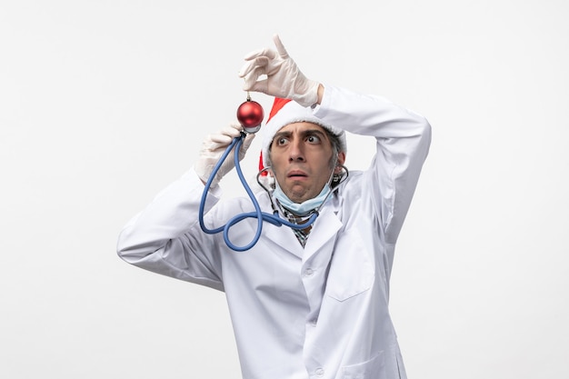 Gratis foto vooraanzicht mannelijke arts speelgoed op witte muur virus covid gezondheid nieuwjaar observeren
