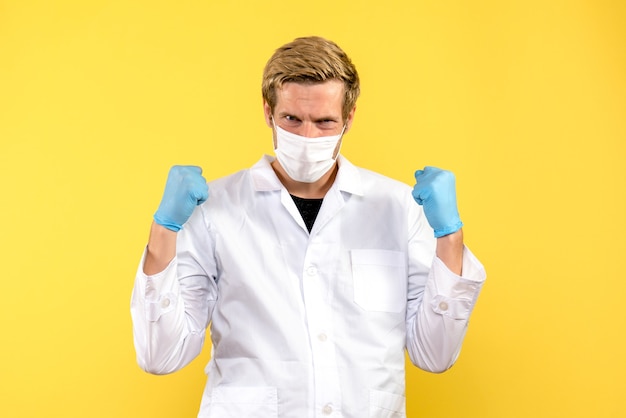 Vooraanzicht mannelijke arts vreugde op gele achtergrond gezondheid medic pandemie covid-