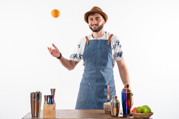 Vooraanzicht mannelijke barman voor bar bureau spelen met fruit op witte muur bar alcohol nacht baan fruit drink club