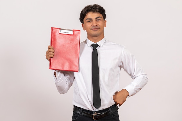 Vooraanzicht mannelijke kantoormedewerker met rood bestand op witte muur kantoorwerk baan mens