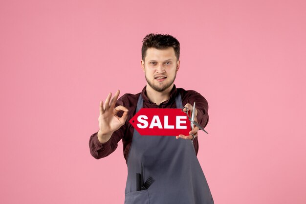 vooraanzicht mannelijke kapper met rood verkoopnaambord op roze achtergrond