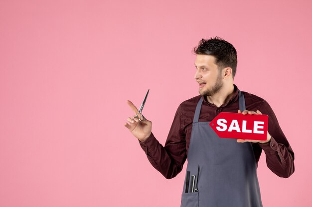 vooraanzicht mannelijke kapper met verkoopnaambord en schaar op roze achtergrond