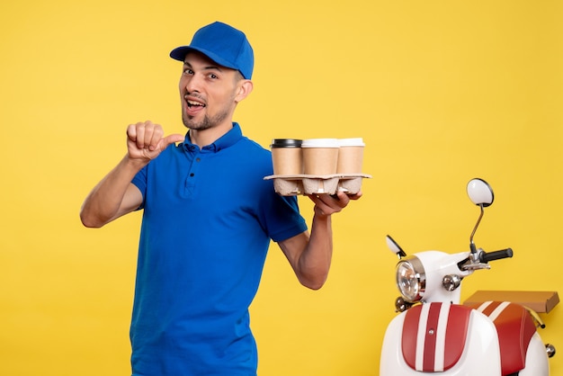 Vooraanzicht mannelijke koerier bezorgen koffie op de gele kleur werknemer service werk levering uniforme fiets baan