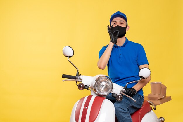Vooraanzicht mannelijke koerier in blauw uniform en masker op gele fiets pandemie werk covid-baan bezorgservice