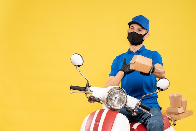 Vooraanzicht mannelijke koerier in blauw uniform op geel baanbezorgingsvirus covid-service fiets pandemie werkvoedsel