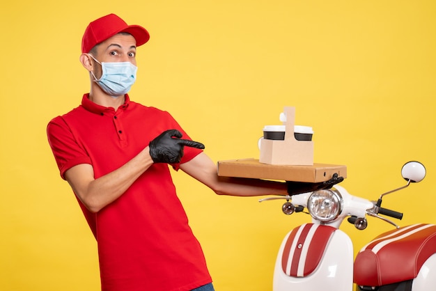 Vooraanzicht mannelijke koerier in masker met bezorgkoffie en doos op de gele dienst covid pandemie kleur virus werk uniform