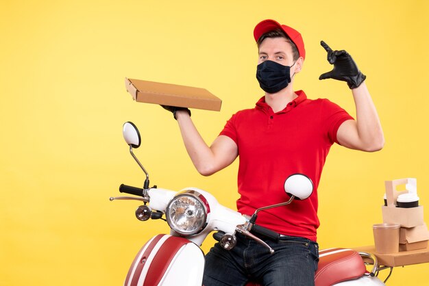 Vooraanzicht mannelijke koerier in masker met voedseldoos op het geel