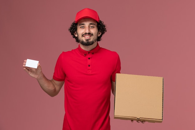 Vooraanzicht mannelijke koerier in rood overhemd en cape met voedselbak en kaart op de roze muur