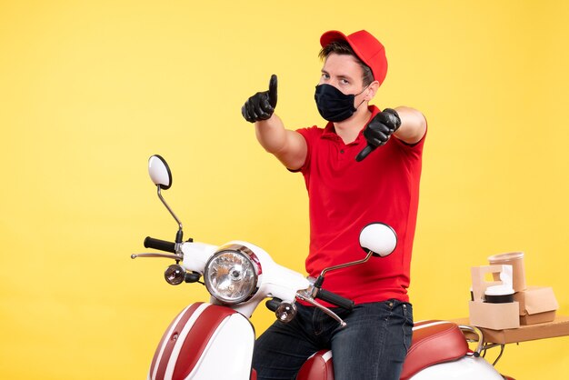 Vooraanzicht mannelijke koerier in rood uniform en masker op geel