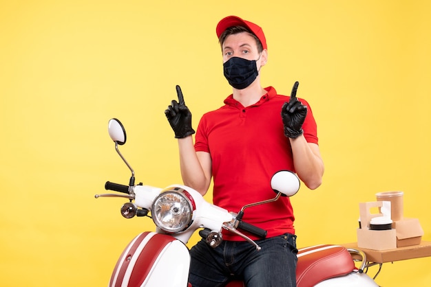 Vooraanzicht mannelijke koerier in uniform en masker op geel