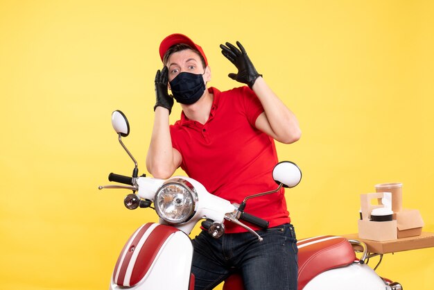 Vooraanzicht mannelijke koerier in uniforme handschoenen en masker op geel