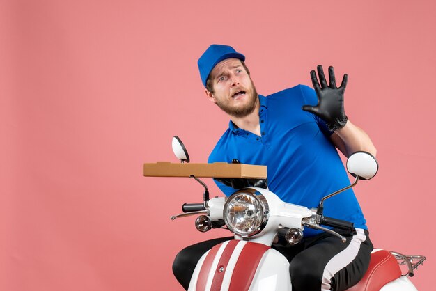 Vooraanzicht mannelijke koerier zittend op de fiets en pizzadoos op het roze te houden