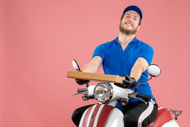 Vooraanzicht mannelijke koerier zittend op de fiets en pizzadoos op het roze te houden