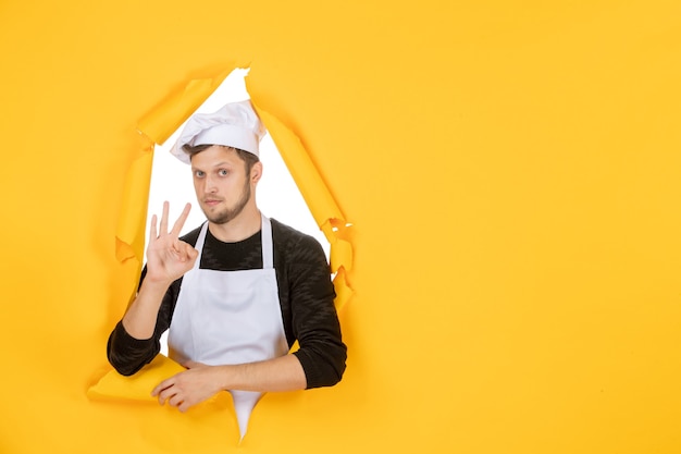 Gratis foto vooraanzicht mannelijke kok in witte cape en pet op gele gescheurde baan kleur witte keuken man keuken foto