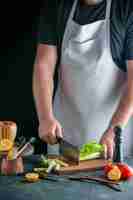Gratis foto vooraanzicht mannelijke kok selderij snijden op donkere muur salade gezondheid dieet maaltijd kleurenfoto