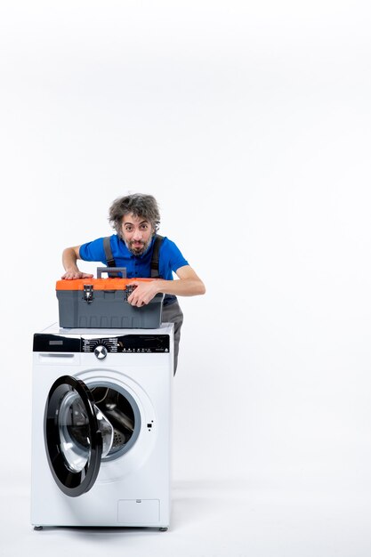 Vooraanzicht mannelijke reparateur die gereedschapstas sluit achter wasmachine op witruimte